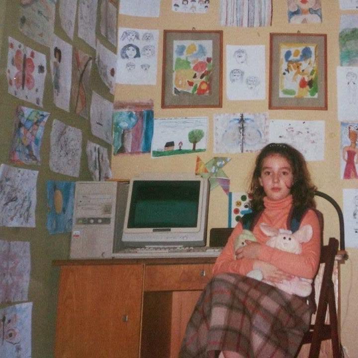 Andreea-Cristina as a child, at her desk, surrounded by her own drawings