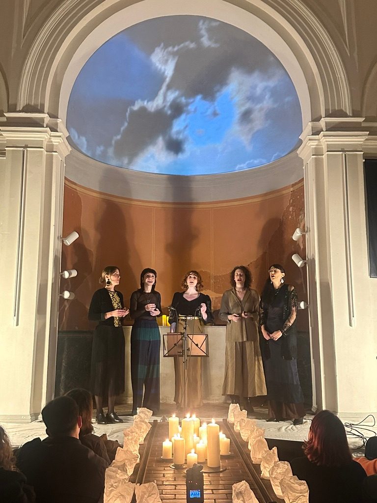 The whole apse from the audience: clouds in the half dome, the five singers, a path of candles