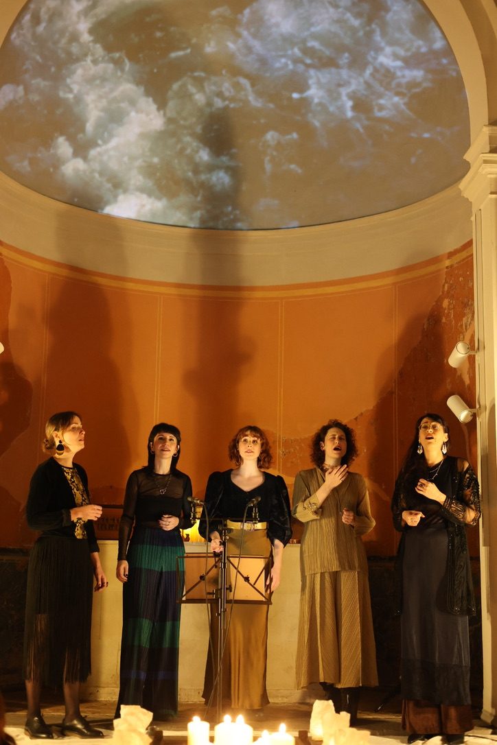 Five singers with candles at their feet, clouds in the half dome above them
