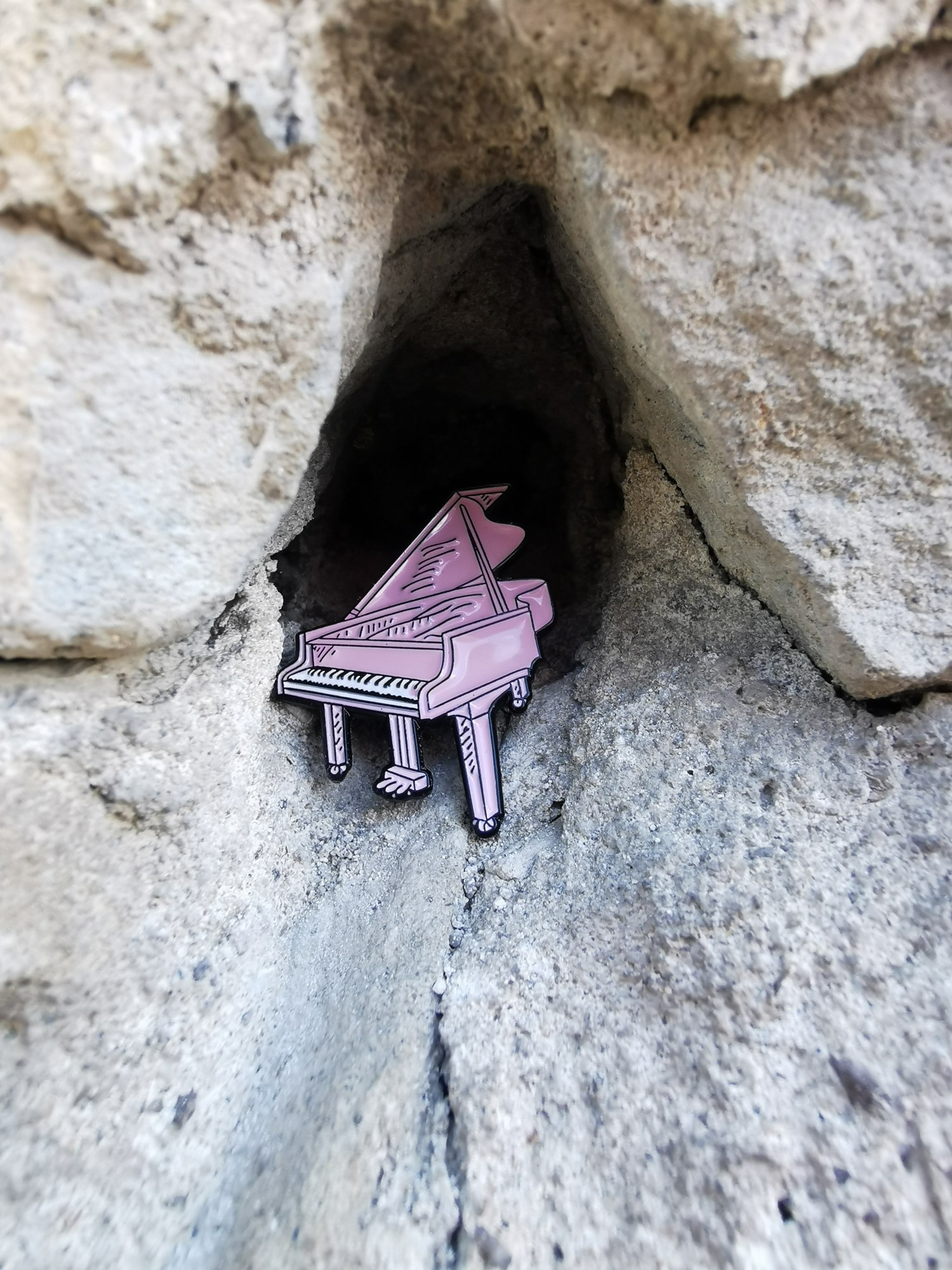 A pink piano pin standing in a hollow of grey rock
