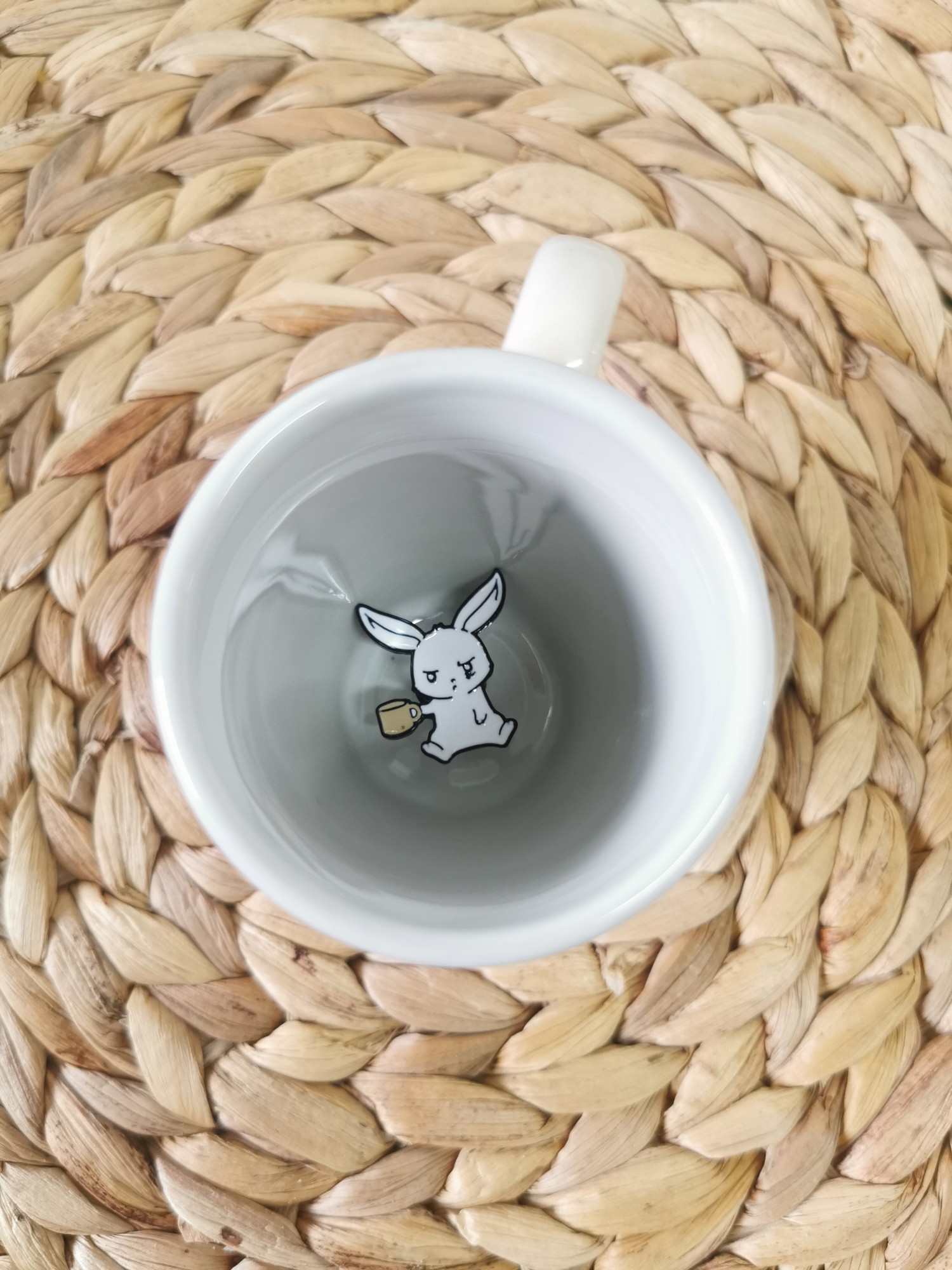 An angry rabbit pin lying in a white cup