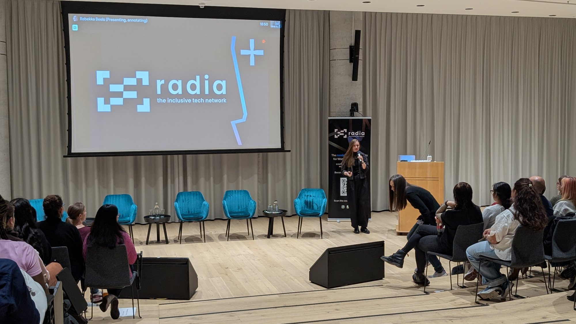 Zalando BHW Auditorium, Berlin, 9 October 2025: the Radia mark on the big screen, the roll-up beside the stage, the room filling up