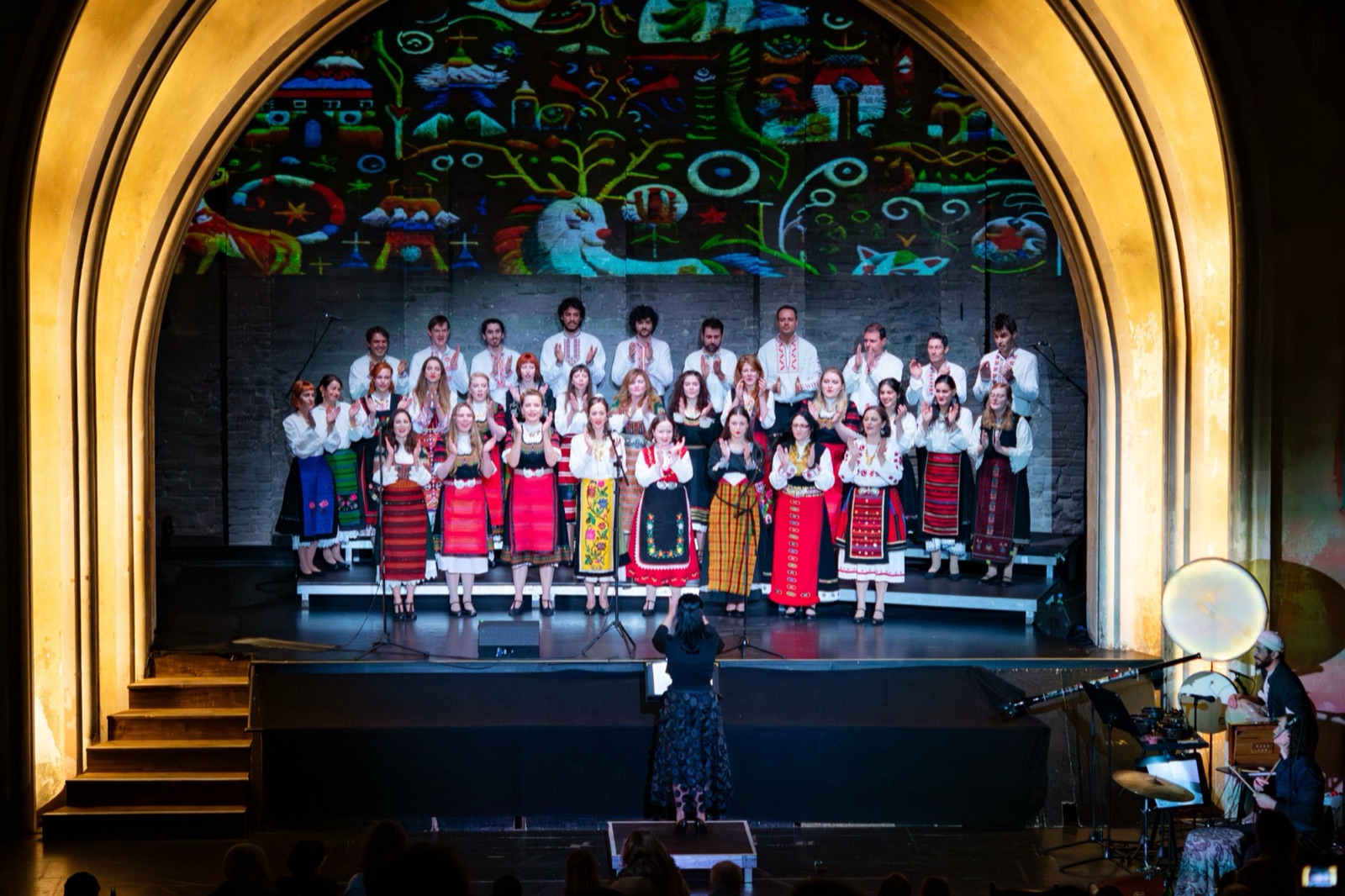 A many-coloured folk pattern projected above the choir