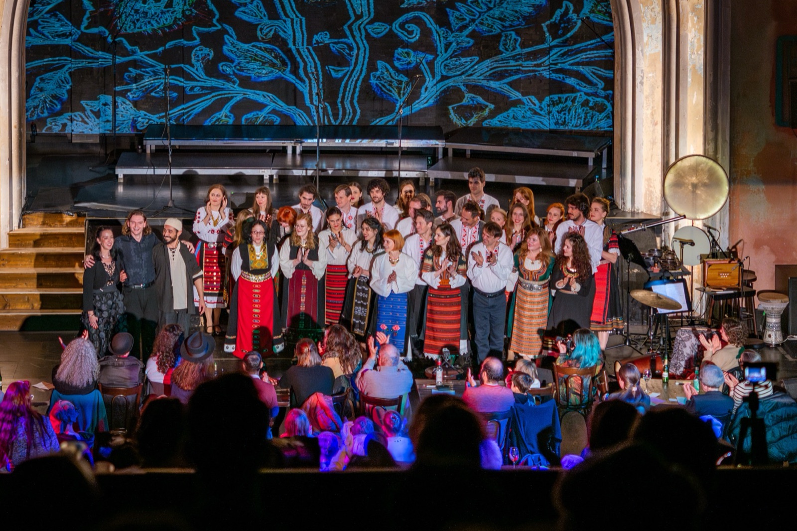 Seen from the audience: a blue tree pattern over the whole stage, choir and musicians below