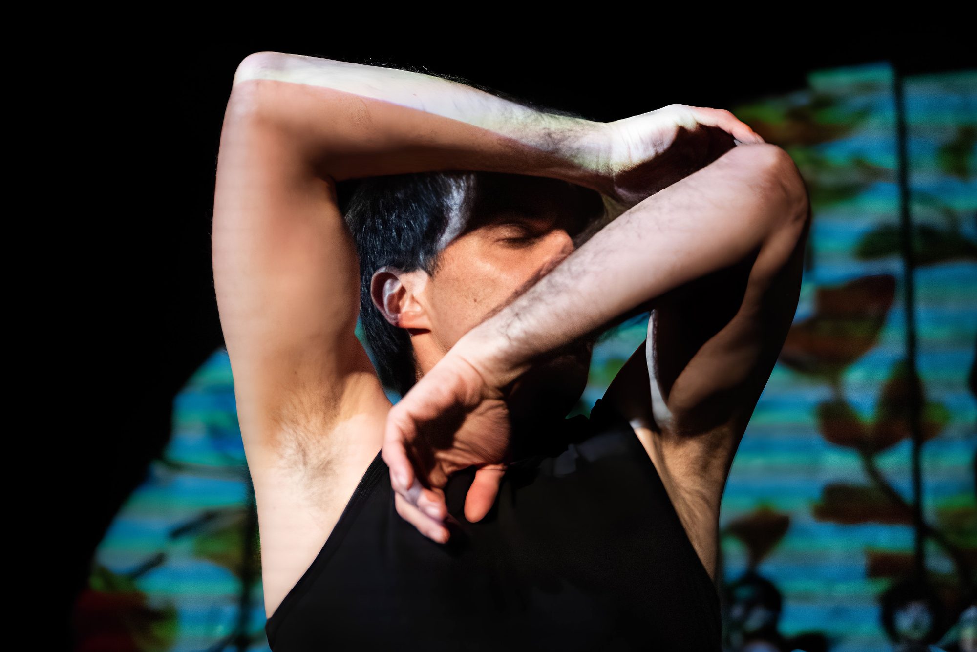 The projected leaves fall across a dancer's raised arms