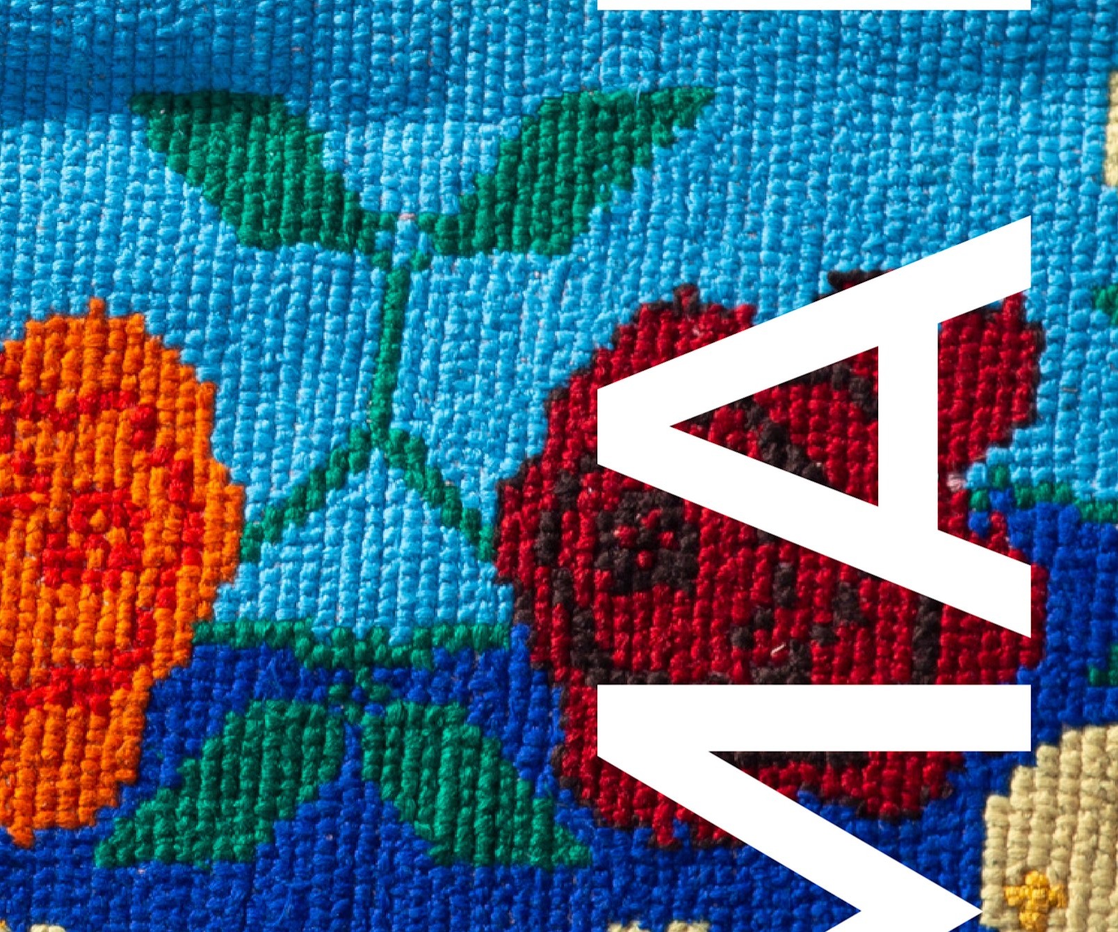 Close-up at print size: the cross-stitched roses beside the white letters of the name